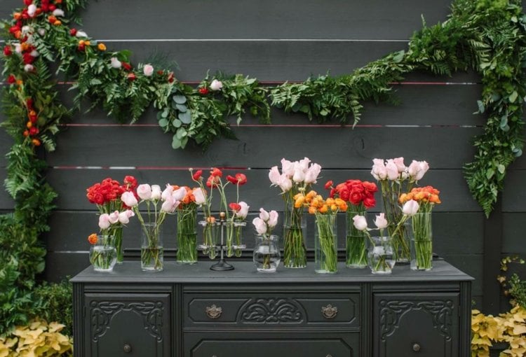 Blumengirlande zur Hochzeit als Hintergrund und Blumen in Vasen