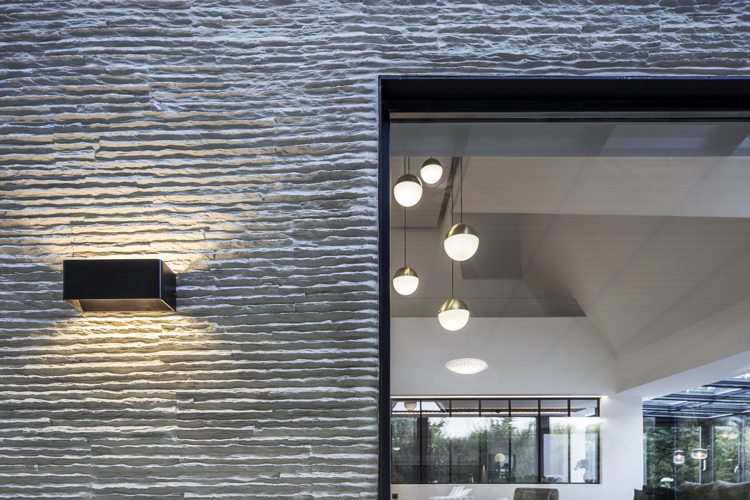 Einfamilienhaus mit Stahlskelettbau Fassade Naturstein verkleidet Beleuchtung Strahler Eingang