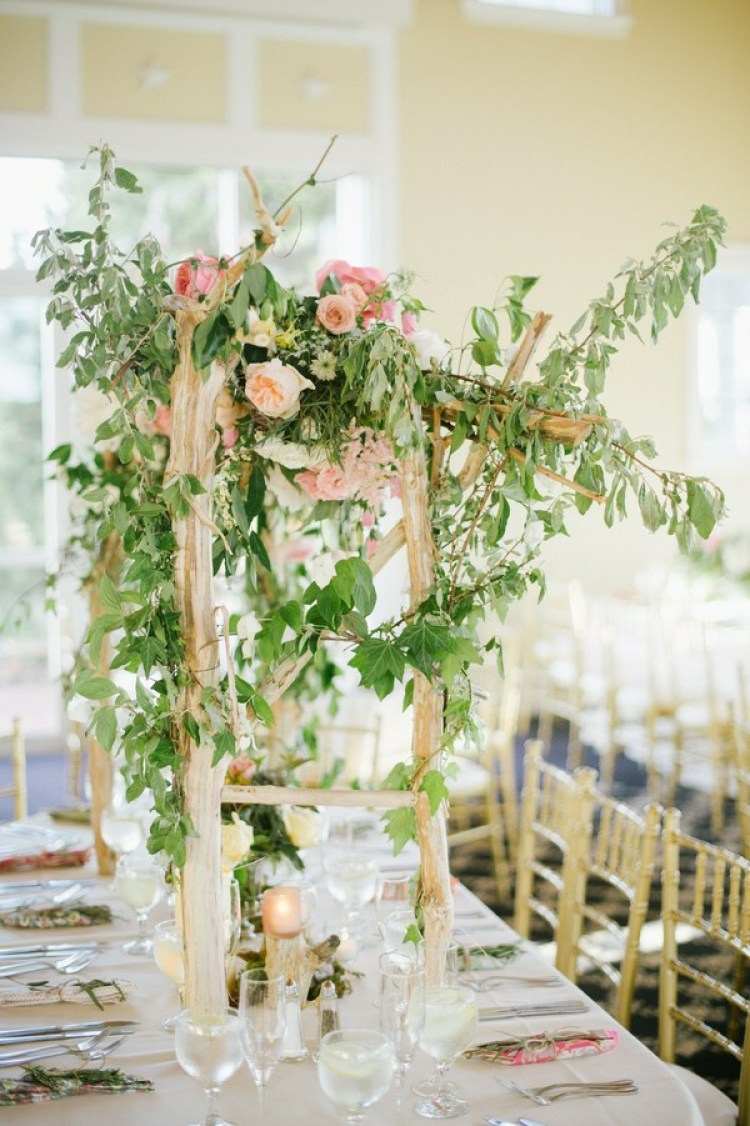 Tischdekoration für den Hochzeitstisch mit grünen Zweigen und Rosen