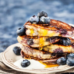 amerikanische Pancakes mit Blaubeeren, Joghurt und Ahornsirup