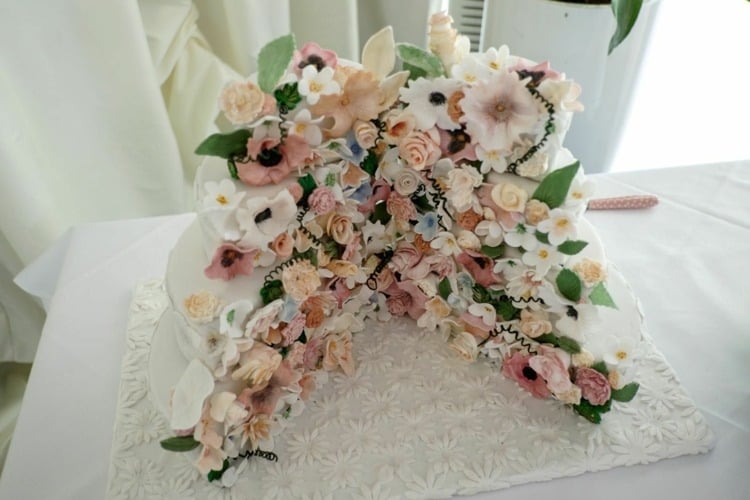 aufgeschnittener Hochzeitskuchen mit floraler Dekoration und schönem Kuchenteller