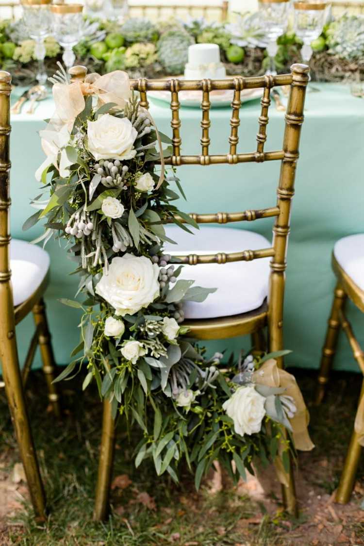 die Stühle auf der Hochzeit mit Blumen schmücken für eine besondere Dekoration