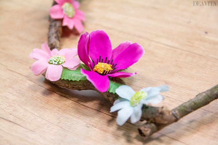 diy kranz aus baumzweigen und kunstblumen in weißen lila und rosa farben dekorieren