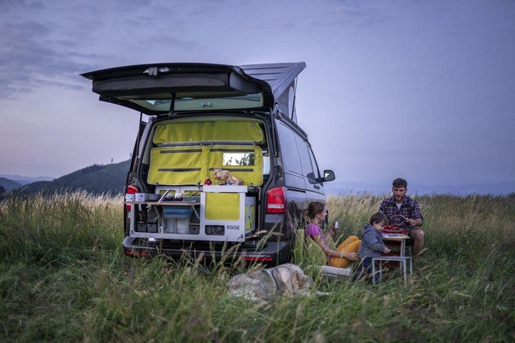 familie mit kind beim abendessen in der natur mit campingfahrzeug ausgerüstet mit campingbox