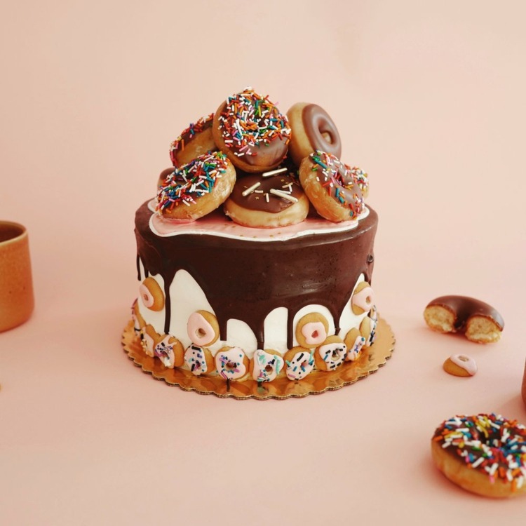 fröhlicher Party Kuchen mit Glasur, Donuts und bunten Streuseln