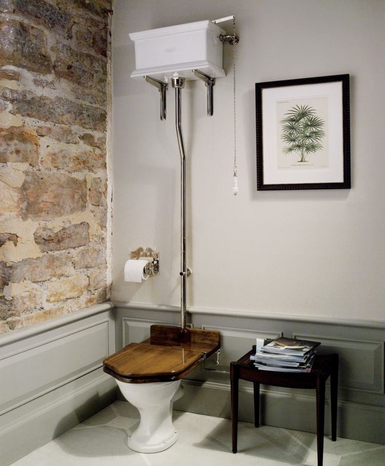 Gemäuer als Akzentwand und antike Möbel und Akzente in einem sparsam eingerichteten Gäste WC