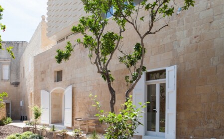 außenfassade vom renovierten kutscherhaus mit weißen türen und garten mit baum in malta