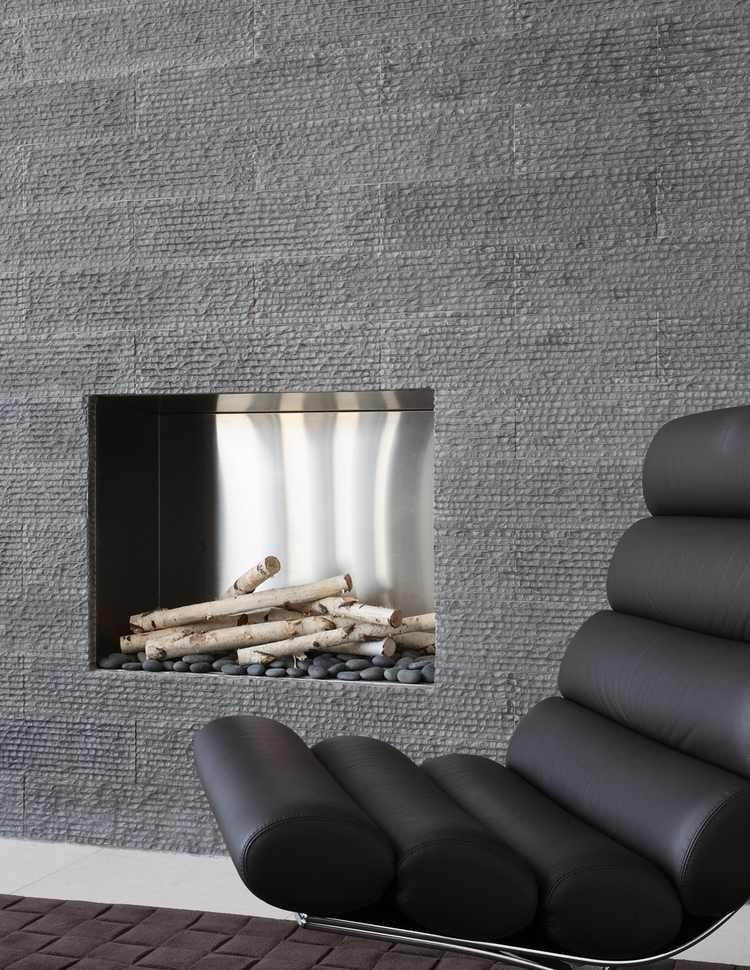 graue steinplatten für wandverkleidung mit integriertem kamin und moderner designer ledersessel