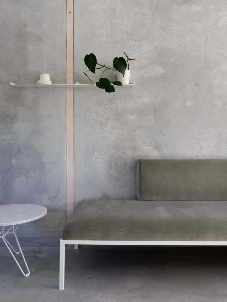 graue wänder aus beton in kombination mit dezenter couch und beistelltisch aus marmor