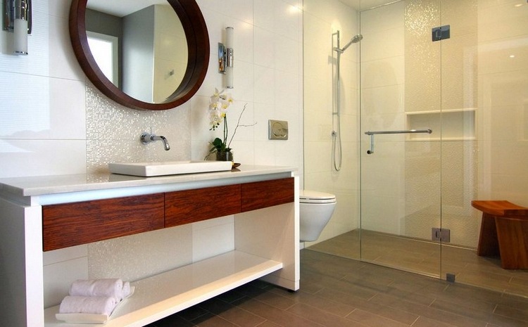 runder spiegel im bad mit duschkabine und glatür vor duschnische aus fliesen waschbecken