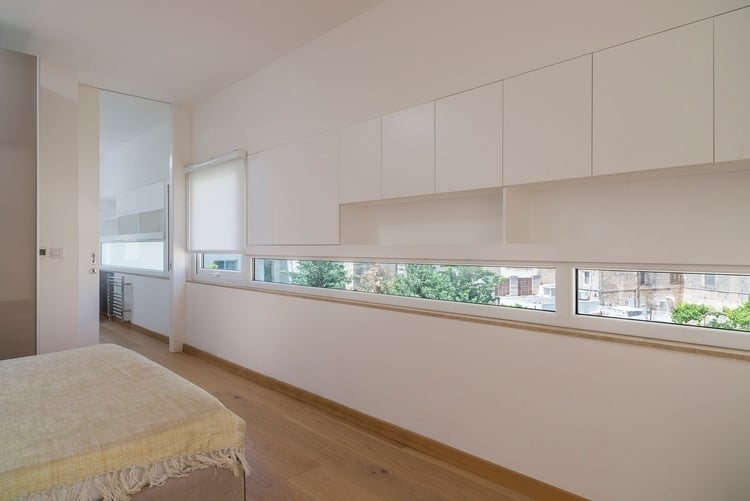 schlafzimmer mit weißer wand und engen fenstern mit sonnenschutz und minimalistisches design