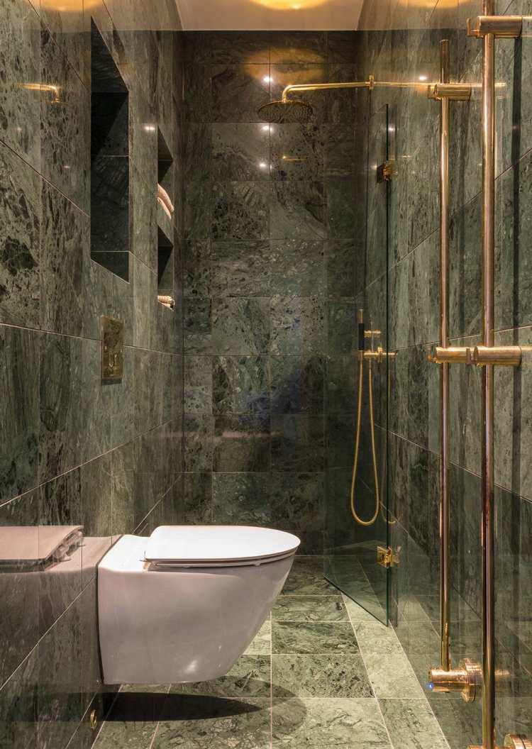schmales Badezimmer Fliesen in Marmoroptik Duschbereich mit Glaswand abgetrennt Messing Armaturen