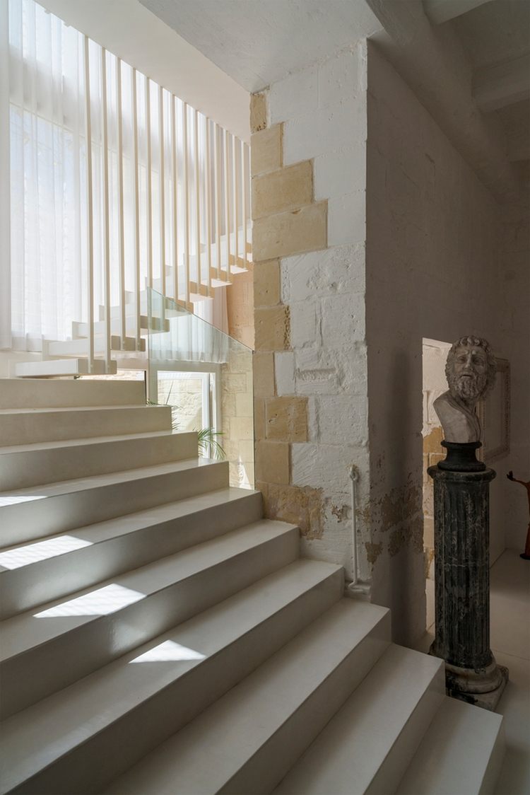 treppenhaus mit fallschutz aus glas und skulptur in beige mit historischen elementen