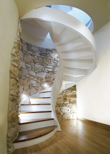 wendeltreppe aus marmor stein und holz in kombination mit steinwand für rustikalen look