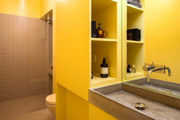 Die Farbe Gelb wird im Bad mit Grau für Fliesen und Beton kombiniert