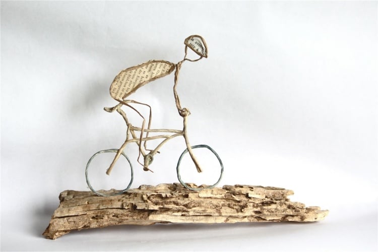Fahrradfahrer mit Helm auf einem Stück Treibholz