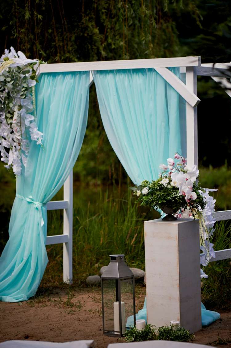 Gartenhochzeit Dekoideen Hochzeitsbogen blauer Vorhang Kerzen