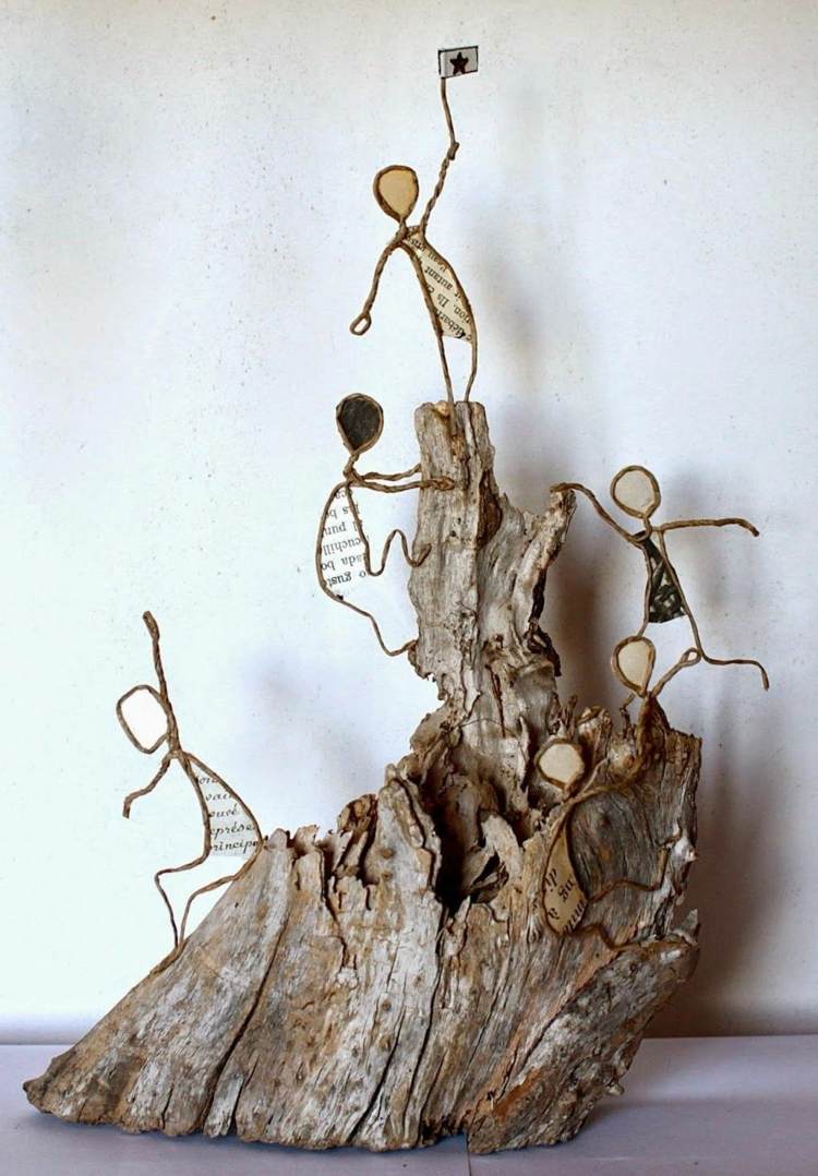 Papierdrahtfiguren erklimmen einen Berg, der aus Holz gemacht ist