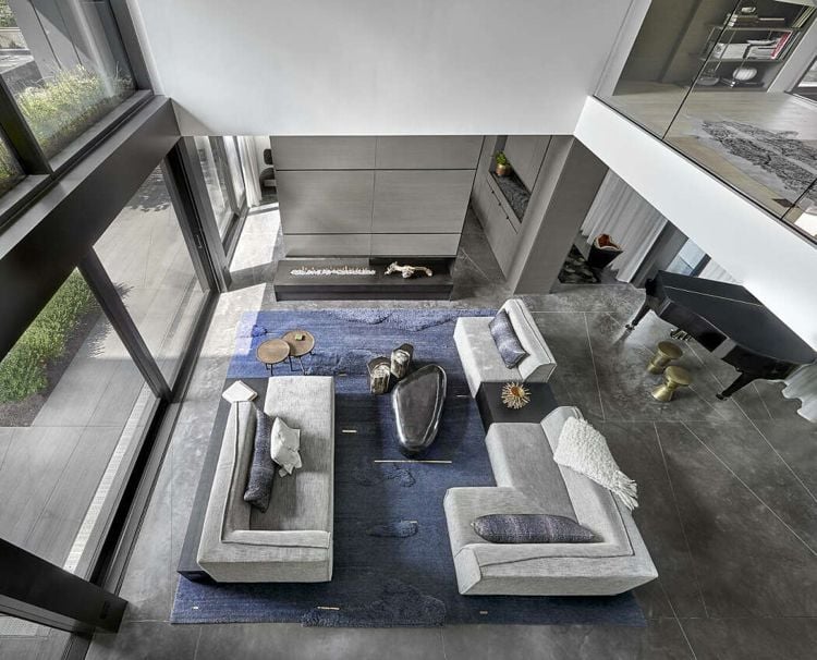 gedeckte Farben Wohnzimmer hohe Decke Teppich blau modulares Sofa Kaffeetisch 3-seitiger Kamin