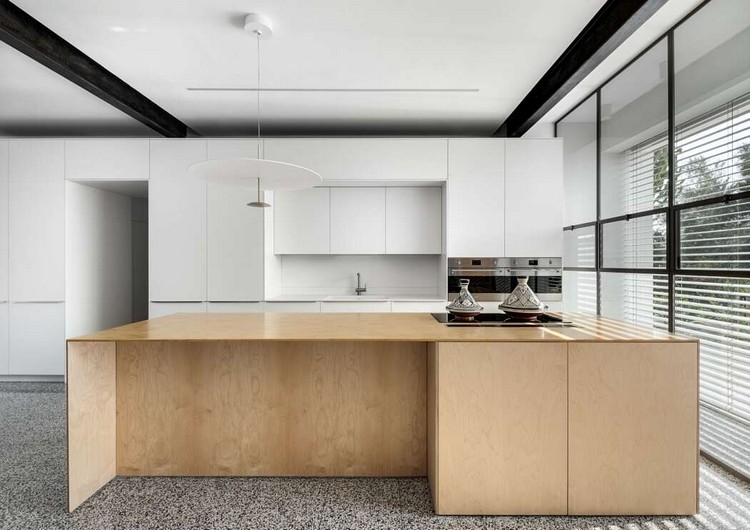 holzfarbene kücheninsel mit essbereich in geräumiger küche mit weißen deckenhohen schränken und fensterfront