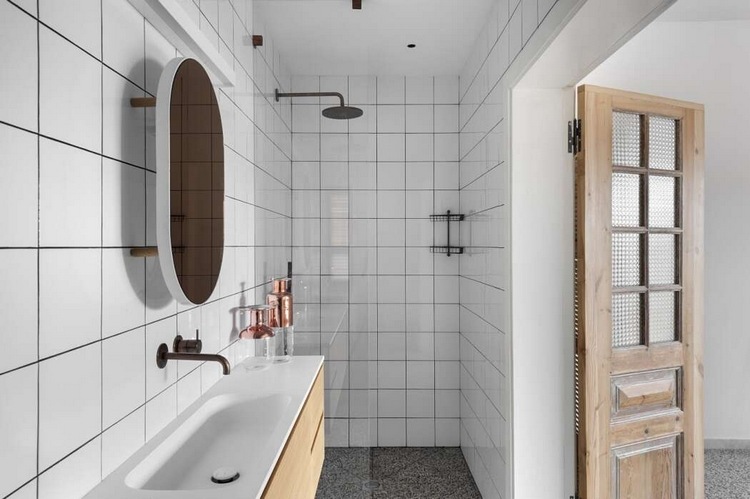 minimalistisches bad mit weißen fliesen duschkabine und holzernen flügeltüren