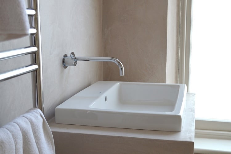 minimalistisches design mit heizkörper und wasserhahn aus metall keramischer waschbecken und steinspachtel kalkputz