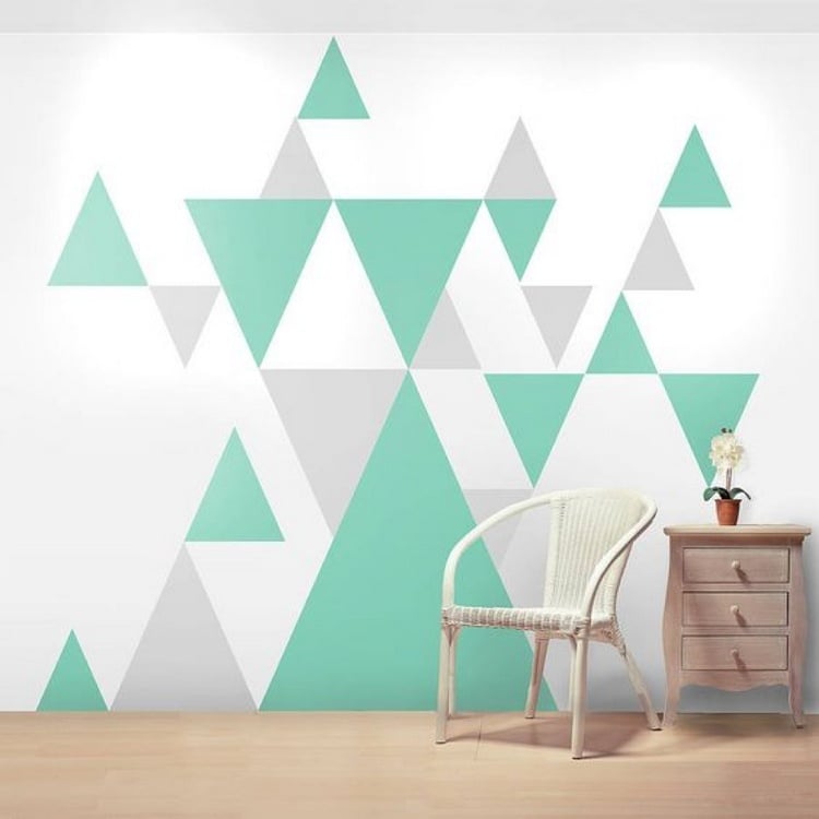 minzgrüne dreiecke als geometrische wandmuster in einem wohnraum mit kommode und stuhl.jpg