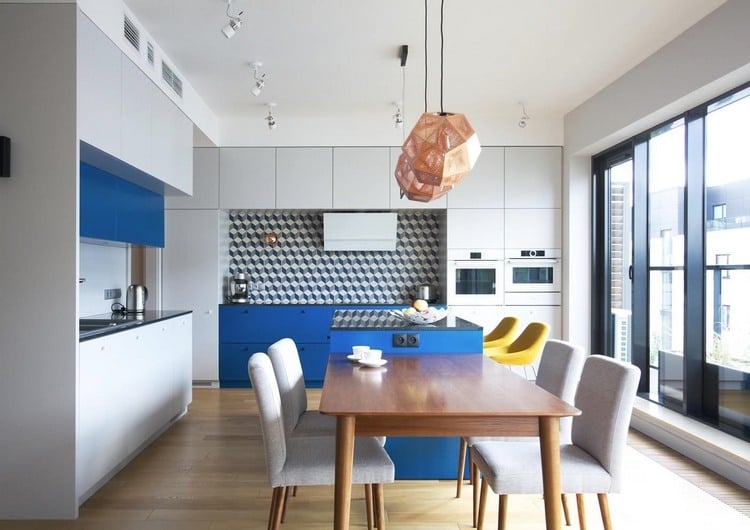 platzsparende erweiterung einer blauen kücheninsel mit esstisch aus holz und küchenstühlen