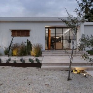 rückseite vom haus mit glasfront und bepflanzten kakteen im sand mit beleuchtung