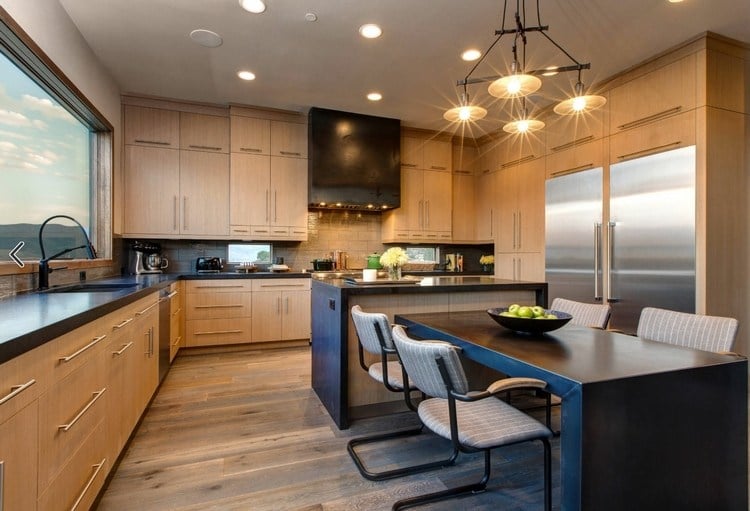 schwarze kücheninsel mit essbereich als l-förmiger tisch mit stühlen in helle küche integrieren