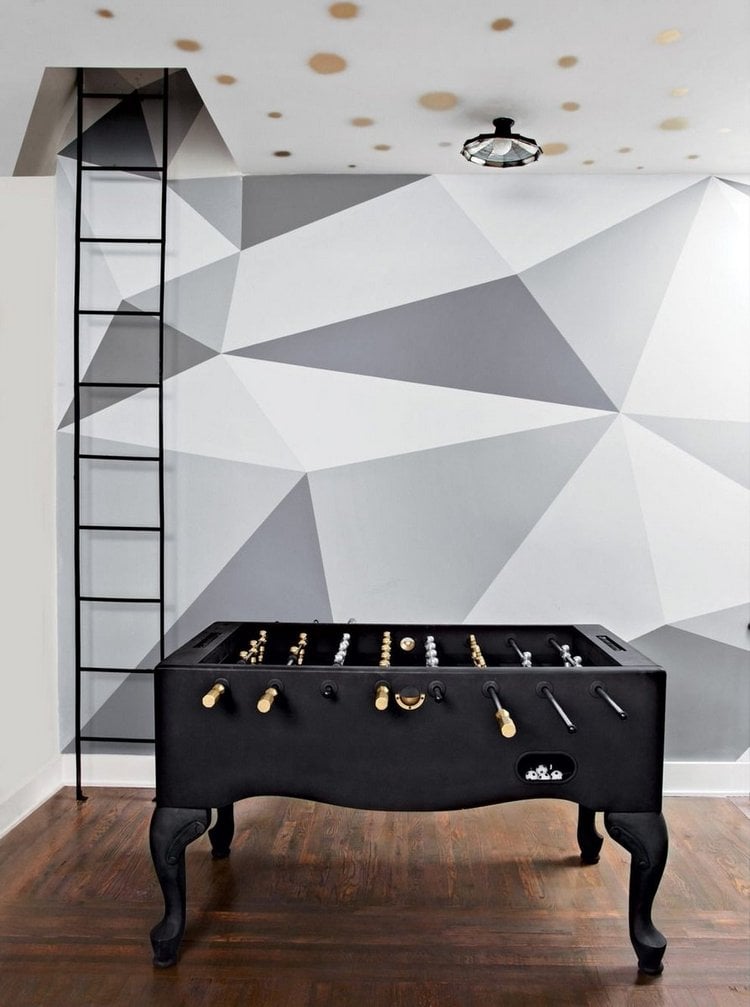 schwarzer designer fußballtisch in einem raum mit geometrischen wandmustern und leiter