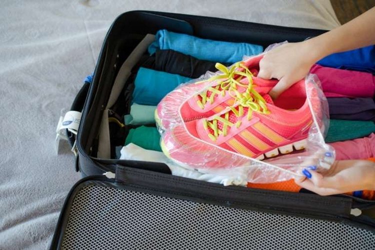 sportschuhe in duschhaube packen und in den koffer neben anderen kleidern anordnen