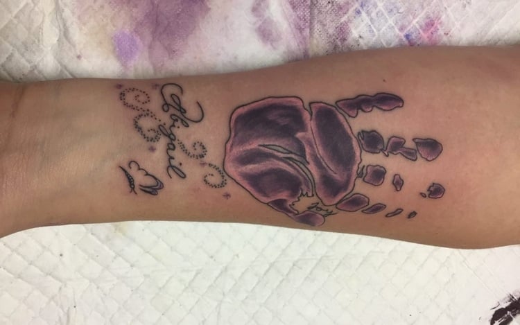 unterarm tattoo mit lilafarbener tätowiertinte und aufschrift zur professionelle nachsorge