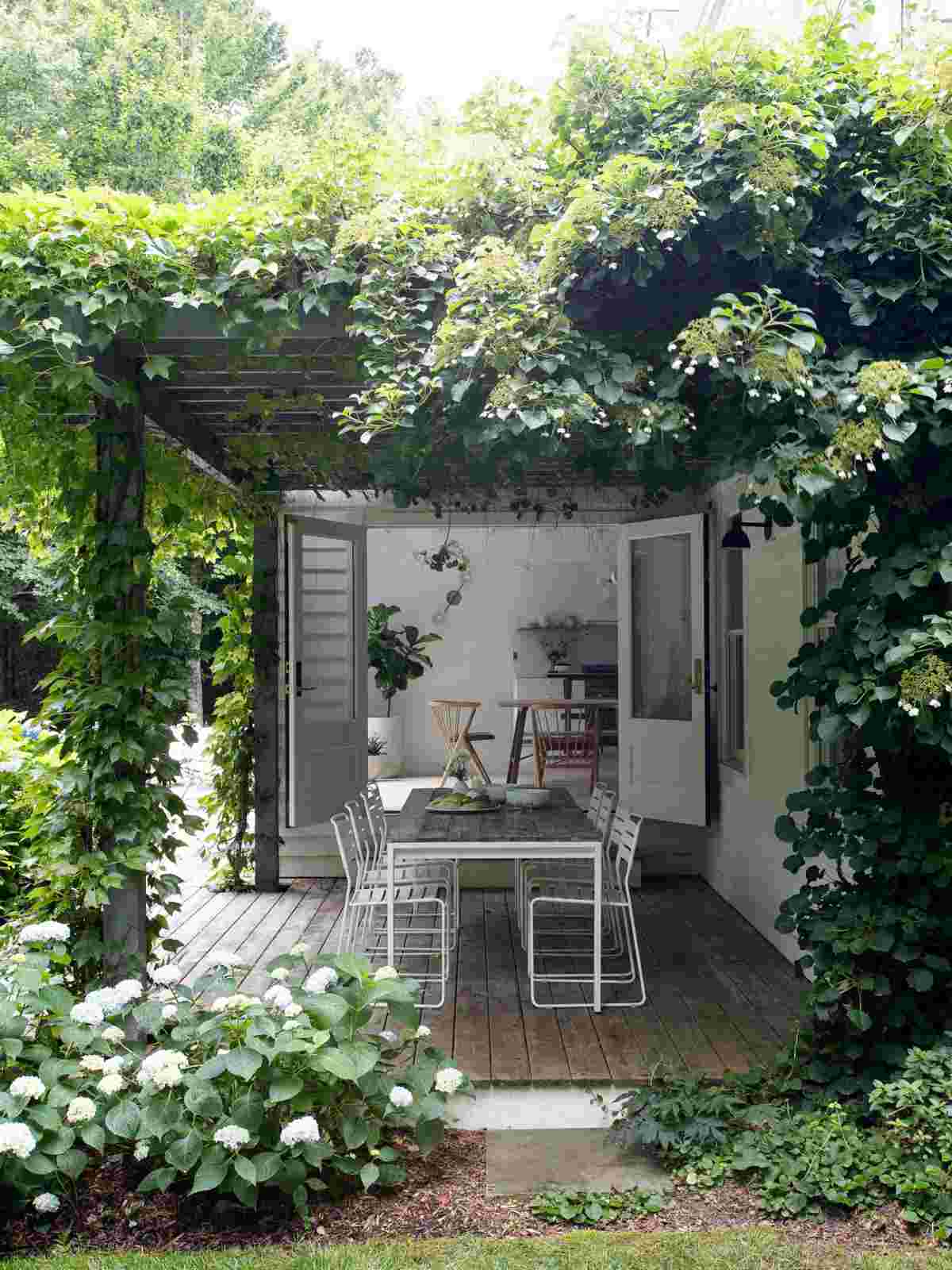 Ein romantischer Cottage-Garten mit skandinavischen Möbeln auf der Terrasse