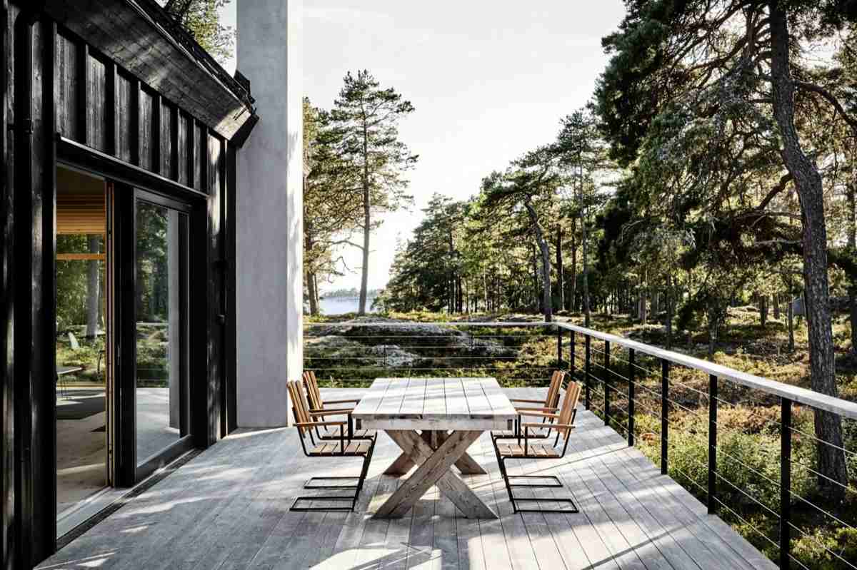 Hohe Terrasse für ein minimalistisch-skandinavisches Haus in Schwarz mit verwittertem Möbel-Design