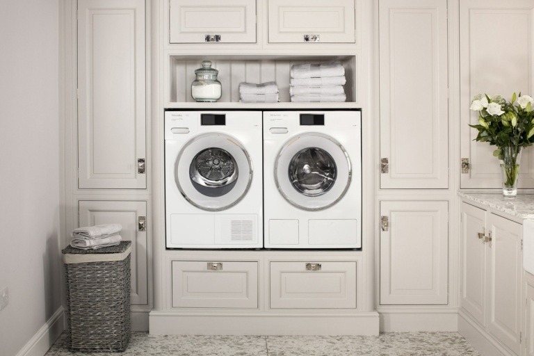 Hohe Waschmaschine und Trockner in einem weißen Einbauschrank