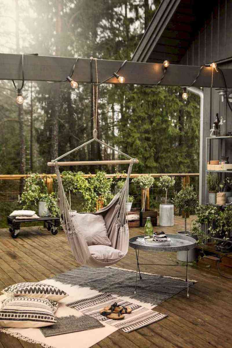 Nordische Terrassengestaltung mit Sitzschaukel, Lichterkette und Teppich