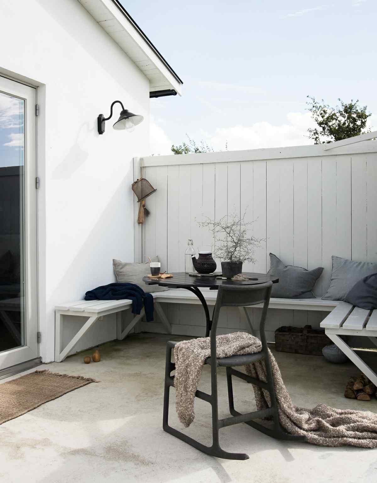Outdoor-Bereich mit Beton Boden, eingebauter Sitzbank und skandinavischem Schaukelstuhl