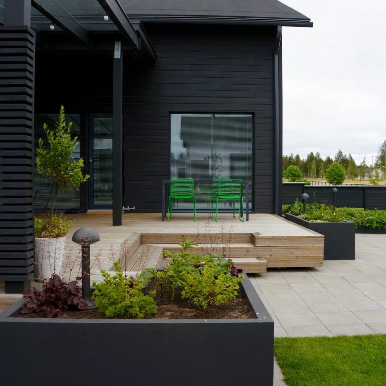 Schwarze Hausfassade aus Holz mit Essbereich aus grünen Stühlen im Scandi-Stil