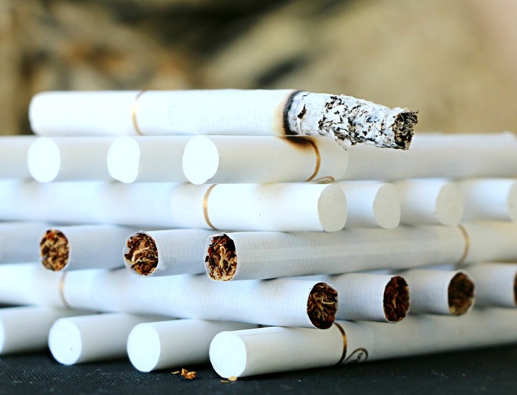 aufeinander gestappelte zigarette mit weißen filtern und eine brennende kippe
