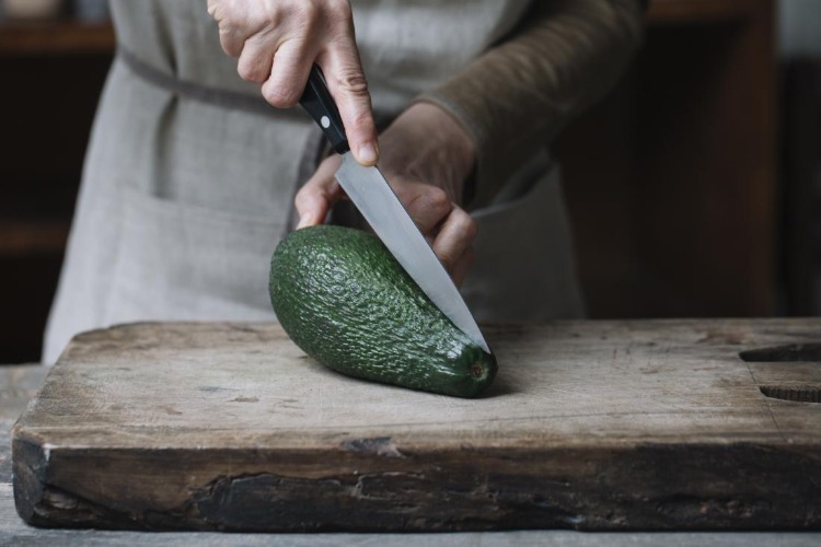 gute lebensmittel für leber wie avocado mit messer schneiden