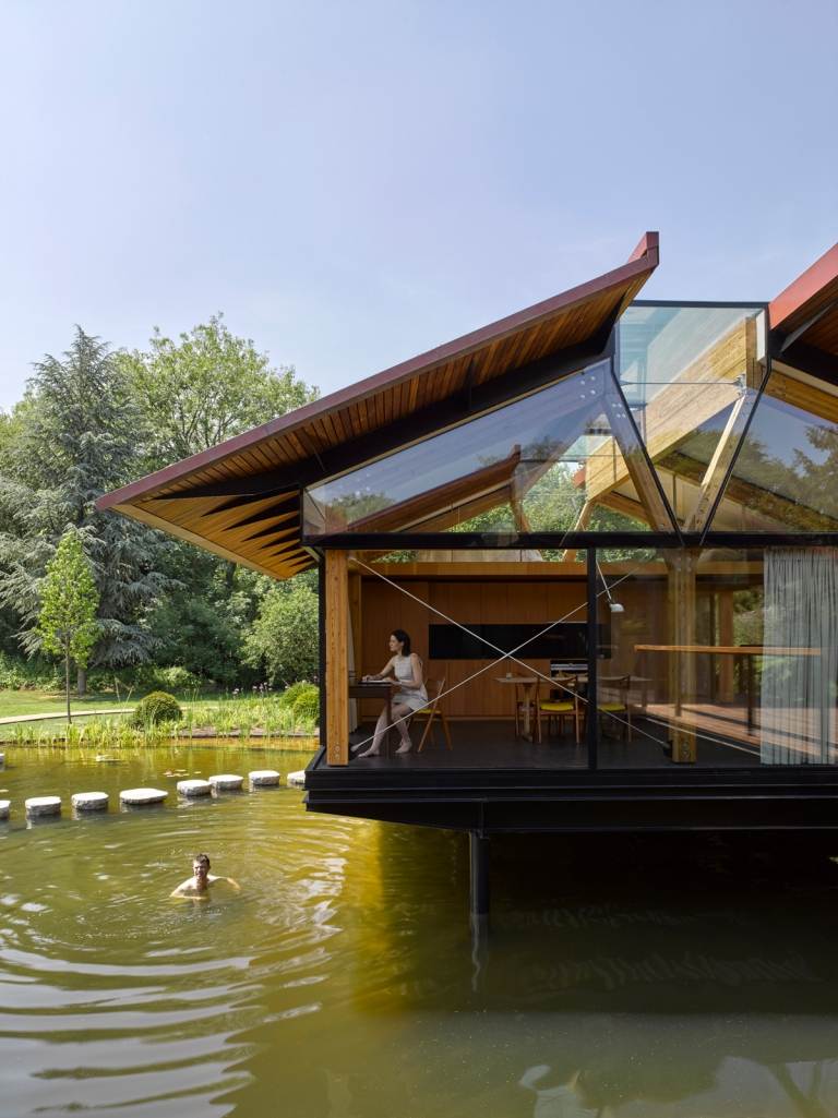 modernes Haus auf Stelzen im Wasser Mann schwimmt im See