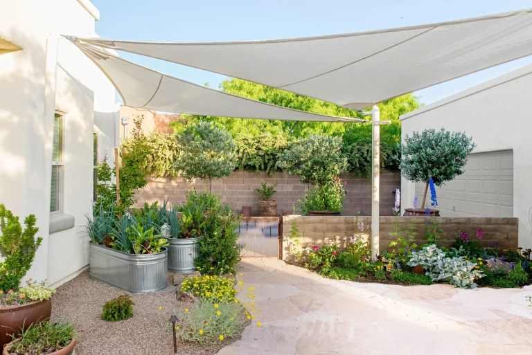 Betonsteine für eine Mauer in einem modernen Garten mit mediterranem Flair und Sonnensegel