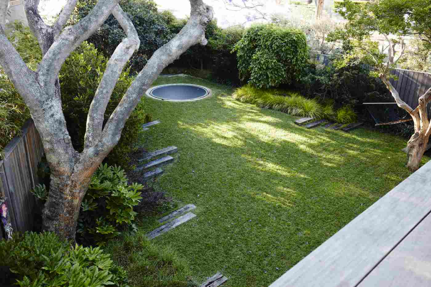 Bodentrampolin im Garten Ecke Bäume Landschaftsbau modern
