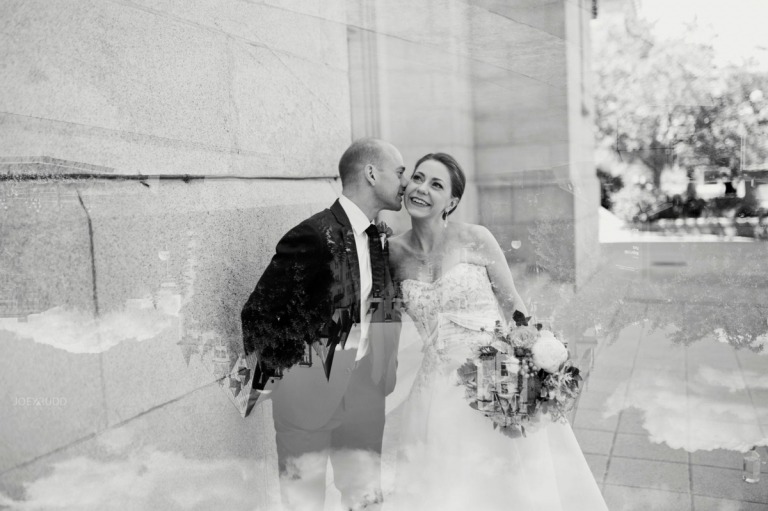 Bräutigam flüstert der Braut etwas zu - Schwarz-Weiß-Foto mit Brautstrauß