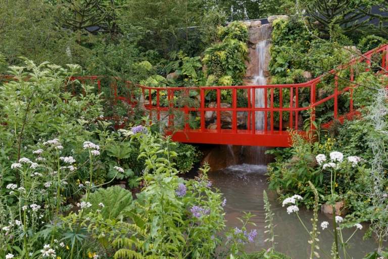 Hoher Wasserfall für den Landschaftsbau mit roter Brücke und Teich