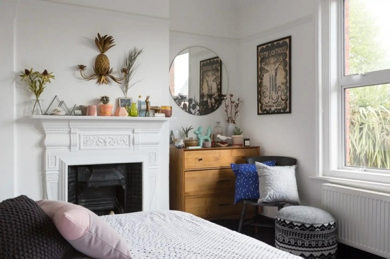 Kleines Schlafzimmer mit Kamin und Kommode mit rundem Spiegel