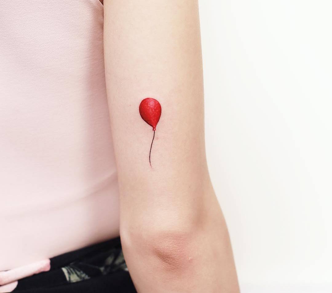 Mini-Tattoo mit einem roten Luftballon auf der Rückseite des Oberarms