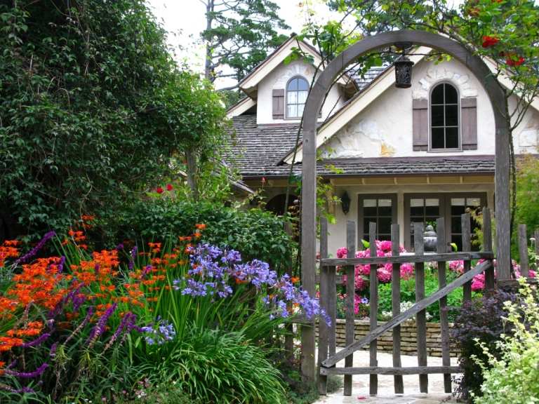 Romantisches Gartentor aus Holz für den englischen Gartenstil und bunte Blüten