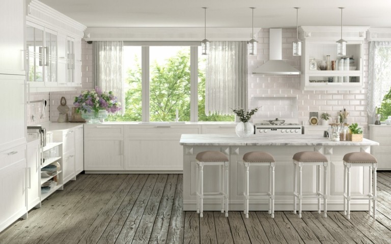 Rustikaler Holzboden in einer weißen Küchen mit großem Fenster und Theke an der Kücheninsel